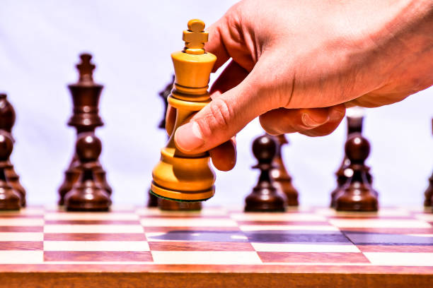 A hand is holding a chess piece, and the piece is on the board, image