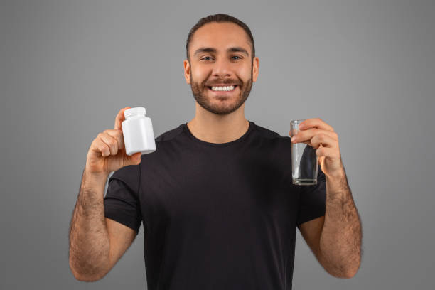 Smiling man holding pill bottle and water