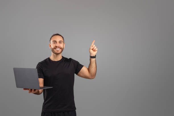 istock Man with a laptop pointing upwards at copy space 2155498399