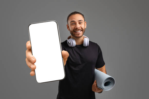 istock Man showing blank phone screen and holding yoga mat 2155498445