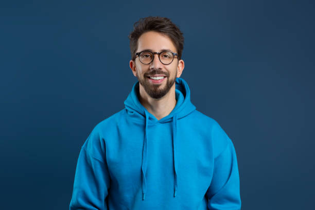 istock Cheerful young man with beard and glasses standing against dark blue background 2155498505