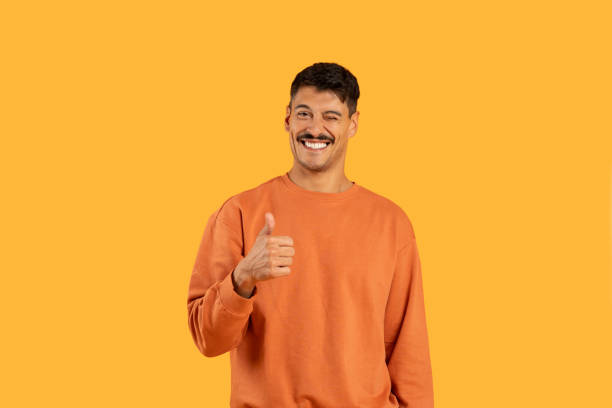 istock Man in an Orange Sweater Giving a Thumbs Up 2155498593