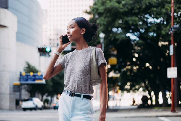 istock Young Woman Talking on Smartphone While Walking in the City 2155498760