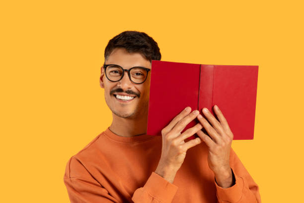 istock Man covering face with book and smiling 2155498823