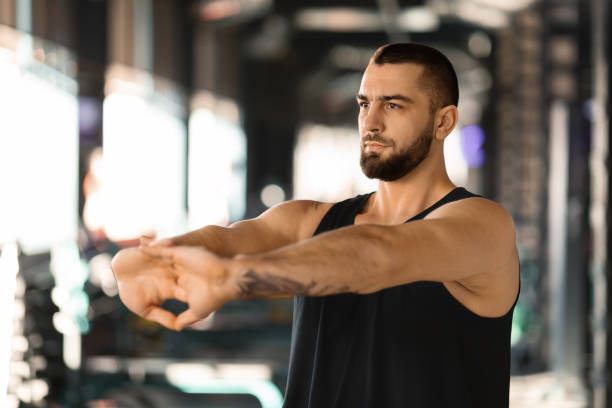 istock Man stretching arms before workout at gym, making hands in lock exercise 2155499000