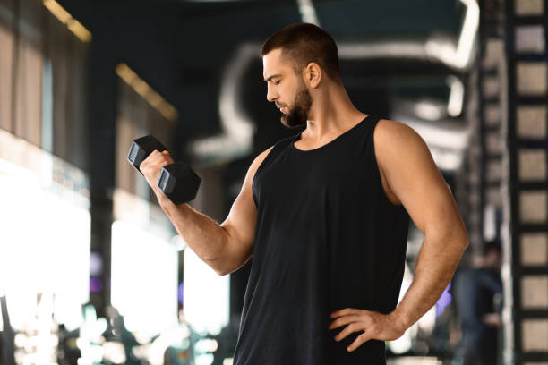 istock Handsome Muscular Young Man Training With Dumbbells In Modern Gym 2155499003