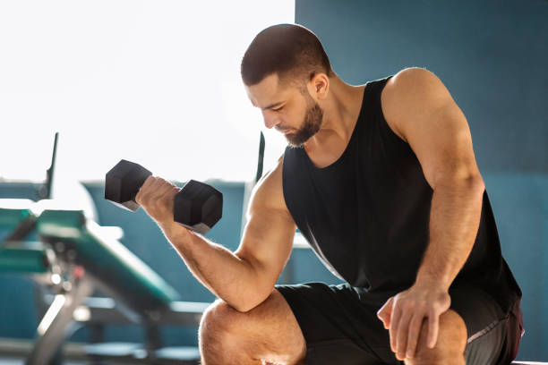 istock Young Male Athlete Training With Dumbbell At Gym, Making Seated Biceps Curl 2155499050