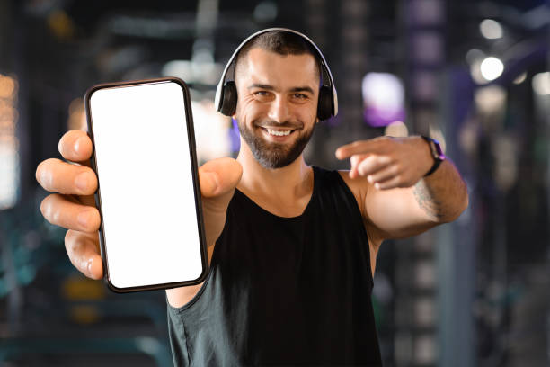 istock Mobile App. Smiling Muscular Man Pointing At Blank Smartphone With White Screen, 2155499073