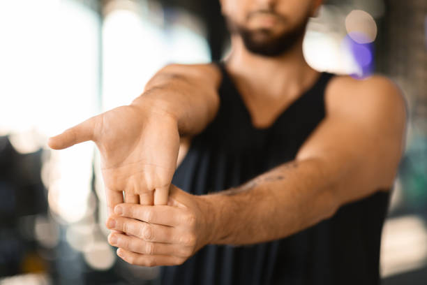 istock Young Man Performing Wrist Stretching Exercise in a Gym Setting 2155499081