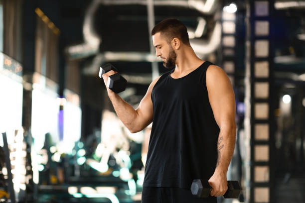 istock Muscular Man Performing Dumbbell Curls at Modern Gym 2155499094