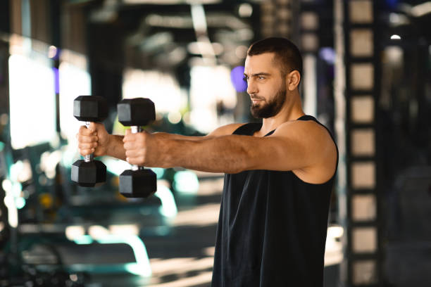 istock Handsome Millennial Man Holding Dumbbells in Gym 2155499095