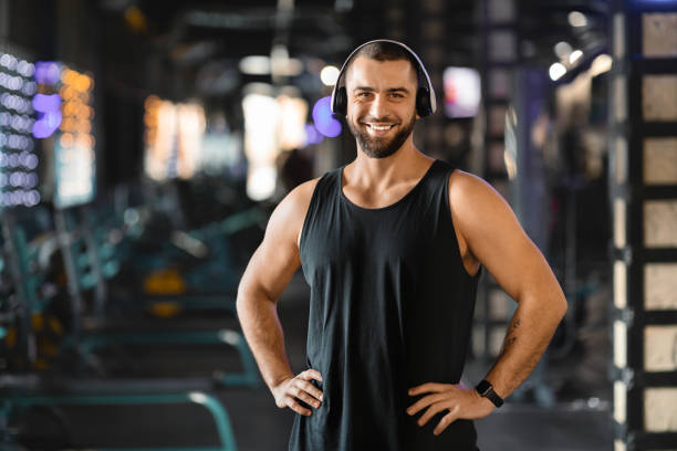 istock Handsome Millennial Man With Headphones Standing in Gym 2155499161