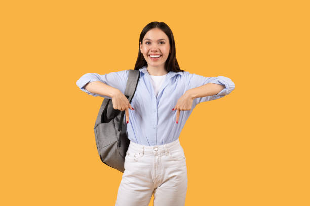 istock Happy female student with backpack pointing down and smiling 2155499873
