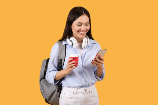 istock Female Student Texting and Holding Coffee Cup 2155499930