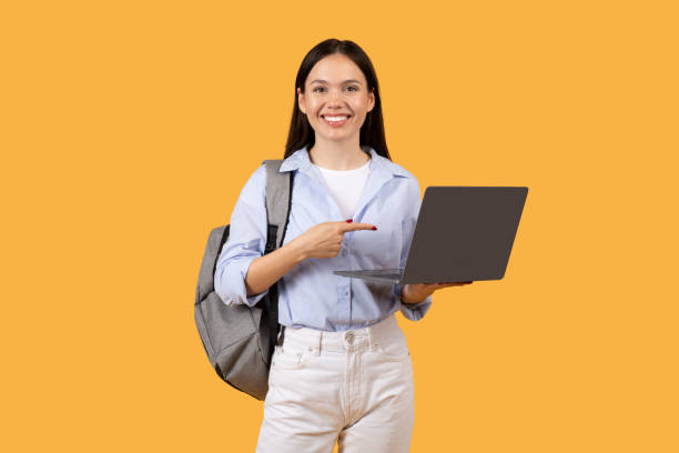 istock Confident female student holding laptop and pointing at screen 2155499953