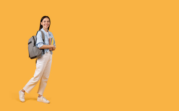 istock Confident student lady walking with notebooks and backpack, ready for day of learning 2155499971