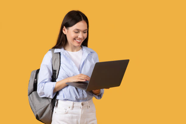 istock Happy Student with Laptop and Backpack against yellow background 2155499986