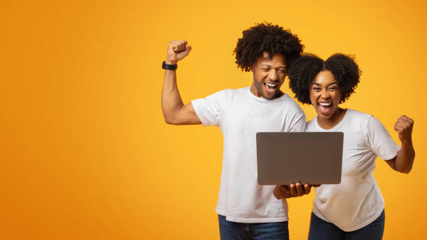 istock Emotional young black couple looking at laptop screen, gesturing 2155500423