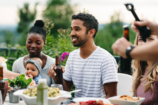 istock Man smiles while enjoying a meal outside with friends 2155500709