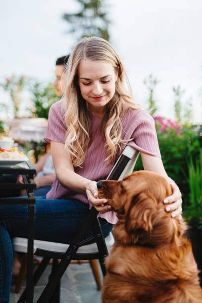 istock Woman feeds obedient pet dog while eating outside 2155500740