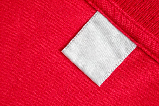 istock Blank white laundry care clothes label on red shirt fabric texture background 2155501645