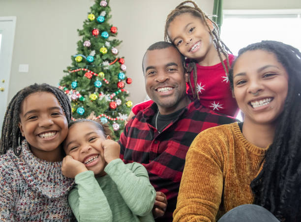 istock A festive scene unfolds as parents and their three elementary-aged daughters exchange Christmas gifts in front of a splendidly adorned tree. 2155501754