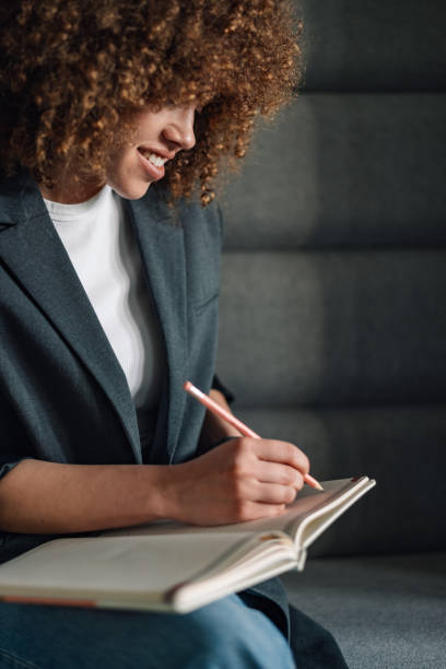 istock Close up of happy creative journalist writing down text in textbook. 2155502494