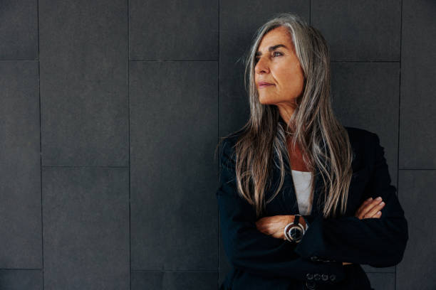 Mature businesswoman on dark background with copy-space