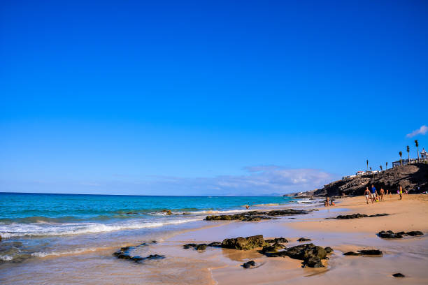istock A beach with a clear blue sky and a few people walking on the sand 2155503219