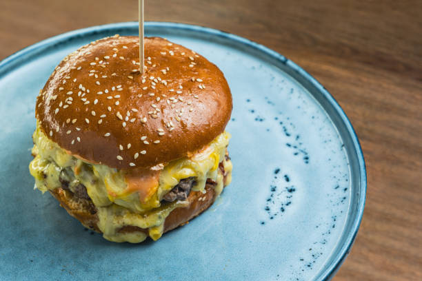 istock Craft cheeseburger with melted cheese served on a plate on a wooden table 2155510753