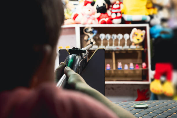 Boy aiming rifle at shooting game booth