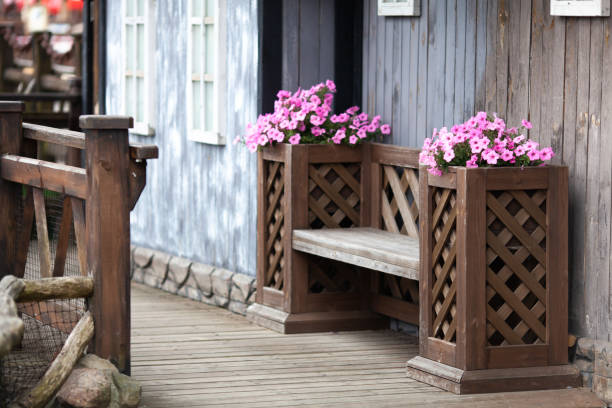 Pink petunia flowers decorating wooden bench. Natural floral composition in city. Modern city gardening, Scandinavian decoration.