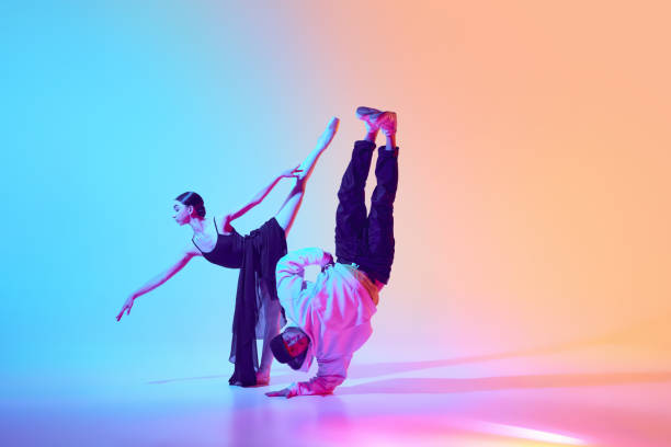 istock Ballerina and breakdancer dancing against gradient background in neon light, highlighting beauty of mixed dance styles 2155514575