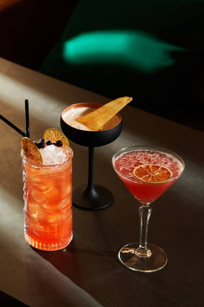 Trio of exquisite refreshing light cocktails with berries and citrus on bar Inviting trio of cocktails: refreshing Zombie with crushed ice and berries, light spiced pear cocktail, and vibrant strawberry daiquiri with dried citrus slice on bar strawberry crush stock pictures, royalty-free photos & images