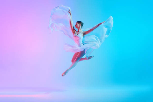 istock Luminous leap. Ballet dancer in white tutu jumping while dancing in motion in neon light against vivid gradient background. 2155519783