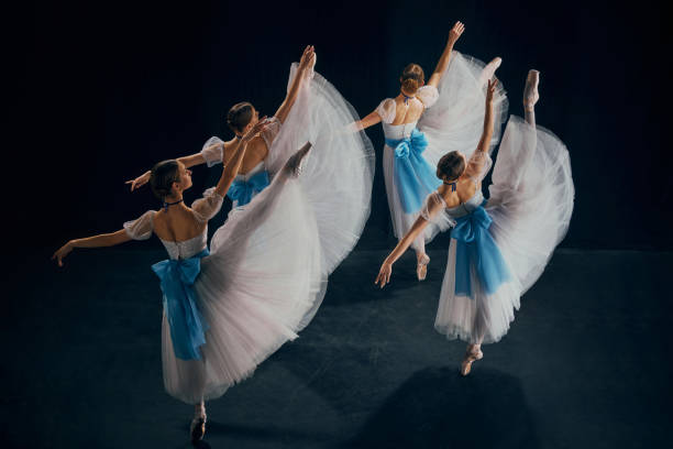 istock Four ballerinas in white and blue costumes performing on stage, each dancer showcasing exquisite balance of strength and grace. 2155520021