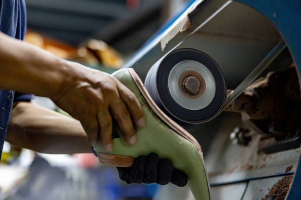 istock Shoemaker working at a factory sanding the sole of a shoe 2155521009