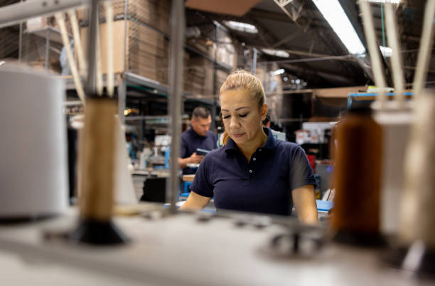 istock Employee working at a shoe factory operating an industrial sewing machine 2155521034