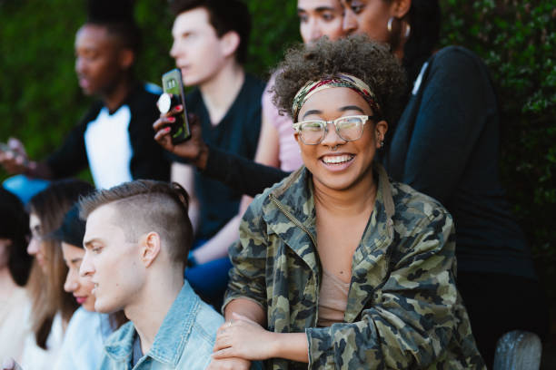 istock Young woman smiles while sitting with her peers outside 2155522547