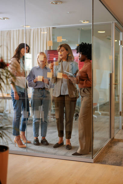 istock Businesswomen making a plan with sticky notes on a glass wall 2155523126