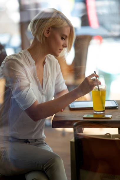 Beautiful young woman checking her digital tablet while enjoying a refreshing drink