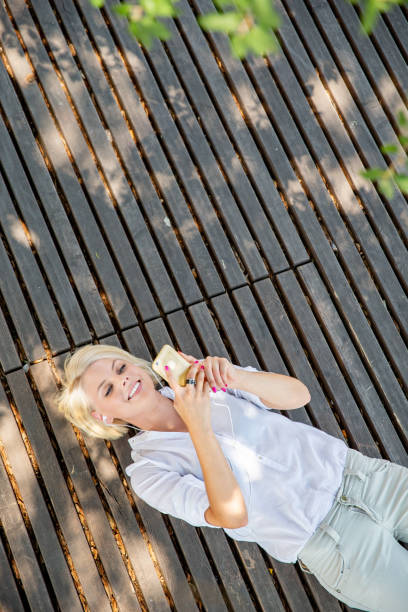 Beautiful young woman lying on back and using her smart phone
