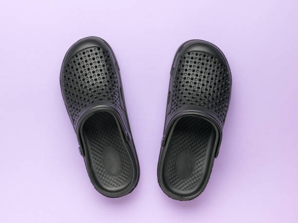 istock Black Rubber Clogs on Lilac Background - Comfortable Casual Footwear 2155524058