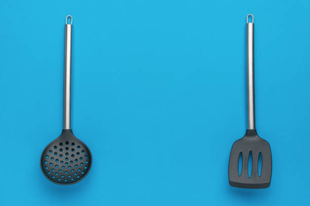 Kitchen Utensils on Blue Background: Strainer Spoon and Slotted Spatula in Minimalist Style