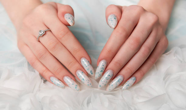 istock Elegant Hands Featuring Sparkling Ring and Blue Floral Manicure on Delicate White Fabric 2155524913