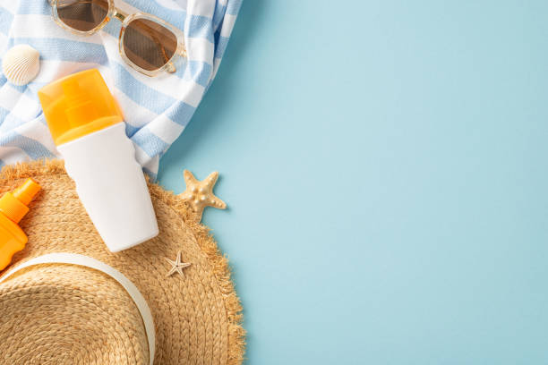 istock Flat lay of summer vacation accessories, featuring sunscreen, sunglasses, and a straw hat on a blue background with a sea theme 2155526459