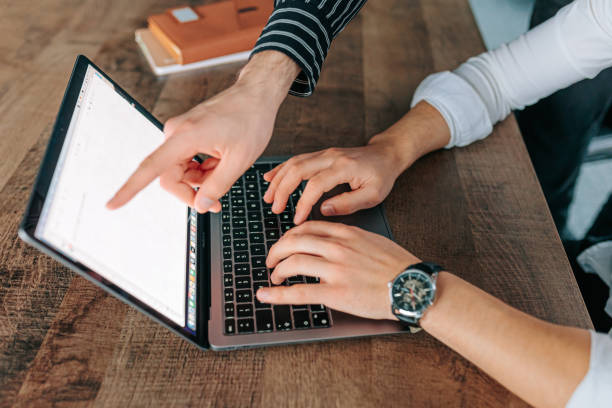 istock An office worker's hands in a close-up, holding a laptop and working intently on it amidst 2155530568