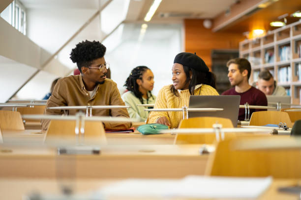 istock Smiling students catching up with each other in a classroom 2155531580