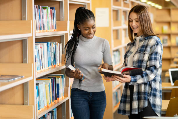 istock Two female friends are checking reference books in a library 2155531585