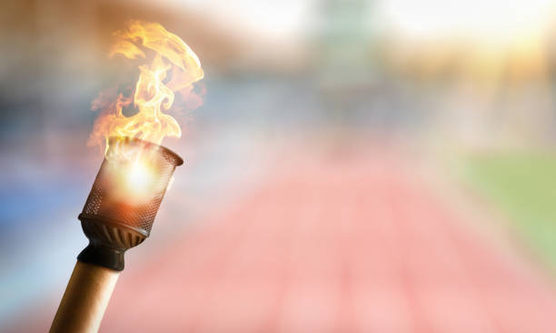 Hand holding torch with athletics stadium behind